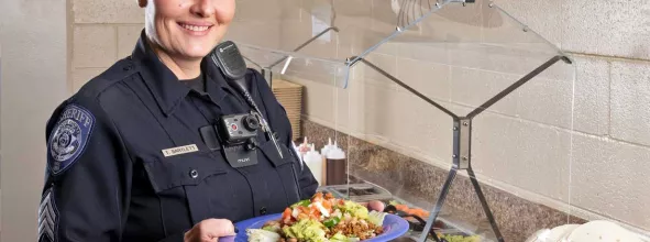 Officer holding a plate of food in cafeteria