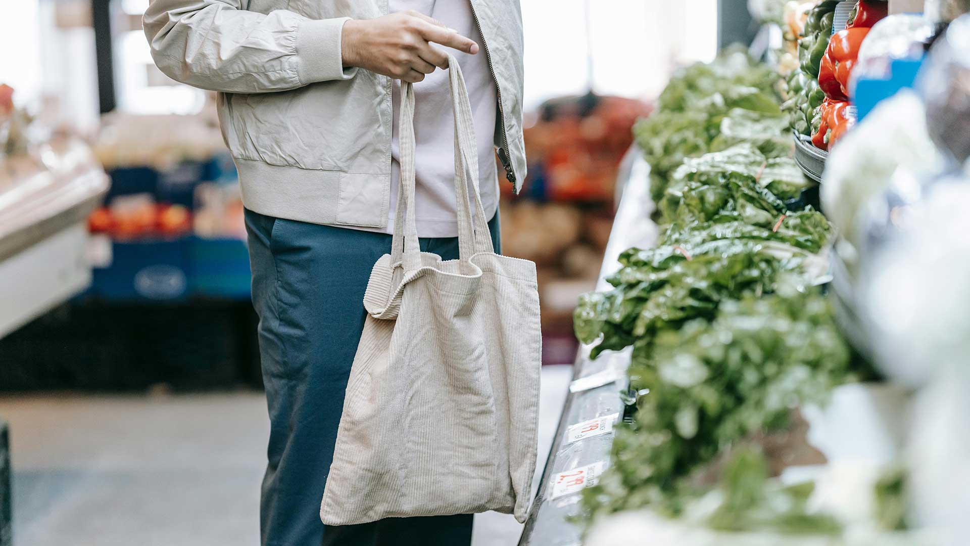 Person holding reusable bag standing in produce aisle