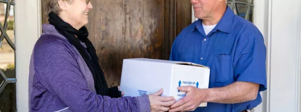 Delivery driver handing packaged meal to customer