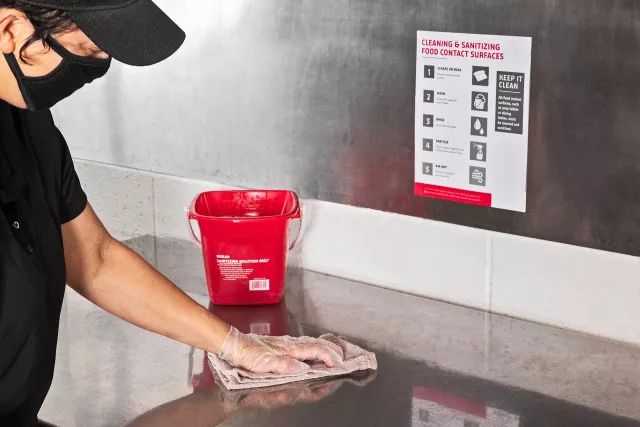 Employee wiping down and sanitizing surface