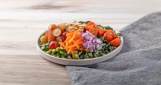 Quinoa salad with assorted vegetables on a wood table with grey napkin