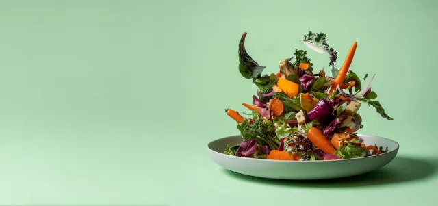 Plate with vegetables falling onto it