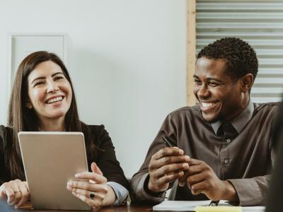 Co-workers overlooking at a tablet while smiling