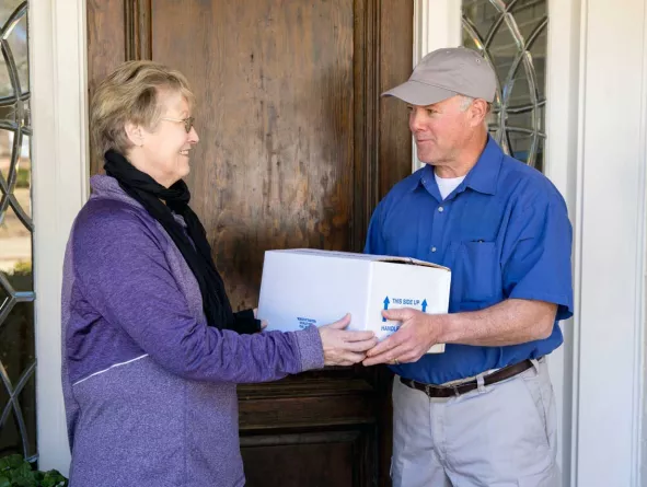 Delivery driver handing packaged meal to customer