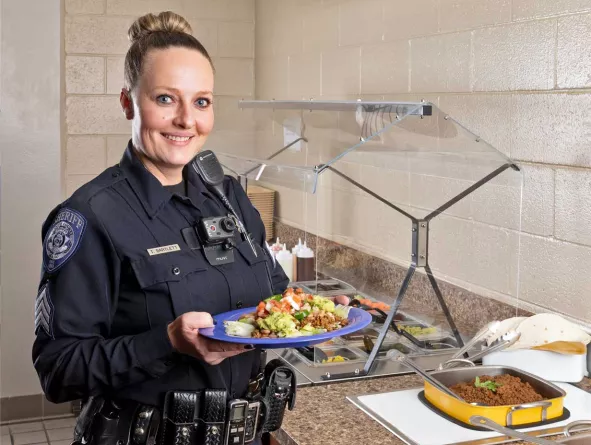Officer holding a plate of food in cafeteria