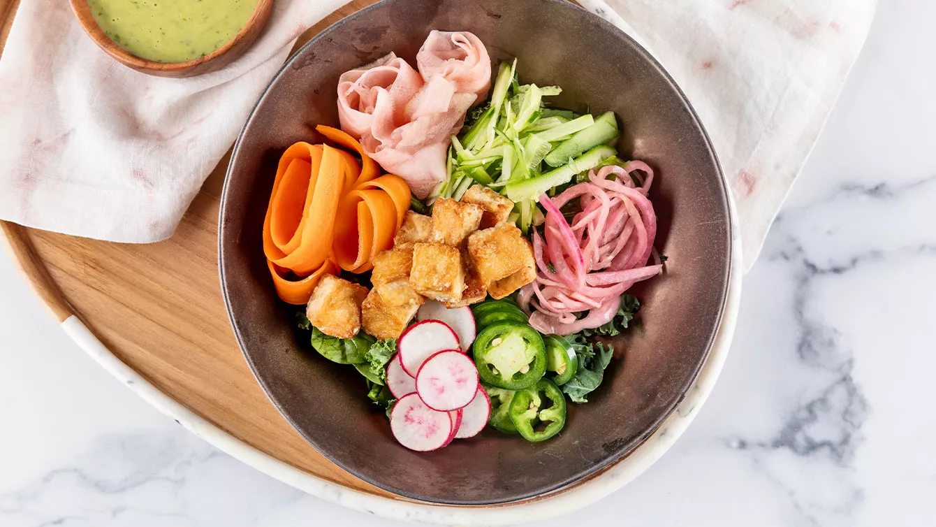 Overhead image of a dish comprised of pickled vegetables and fried tofu in a bowl