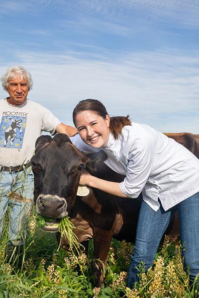 Stacy Wiroll smiling next to farmer and cow Stacy Wiroll smiling next to farmer and cow