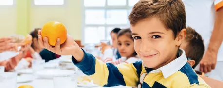 Young school age boy holding orange